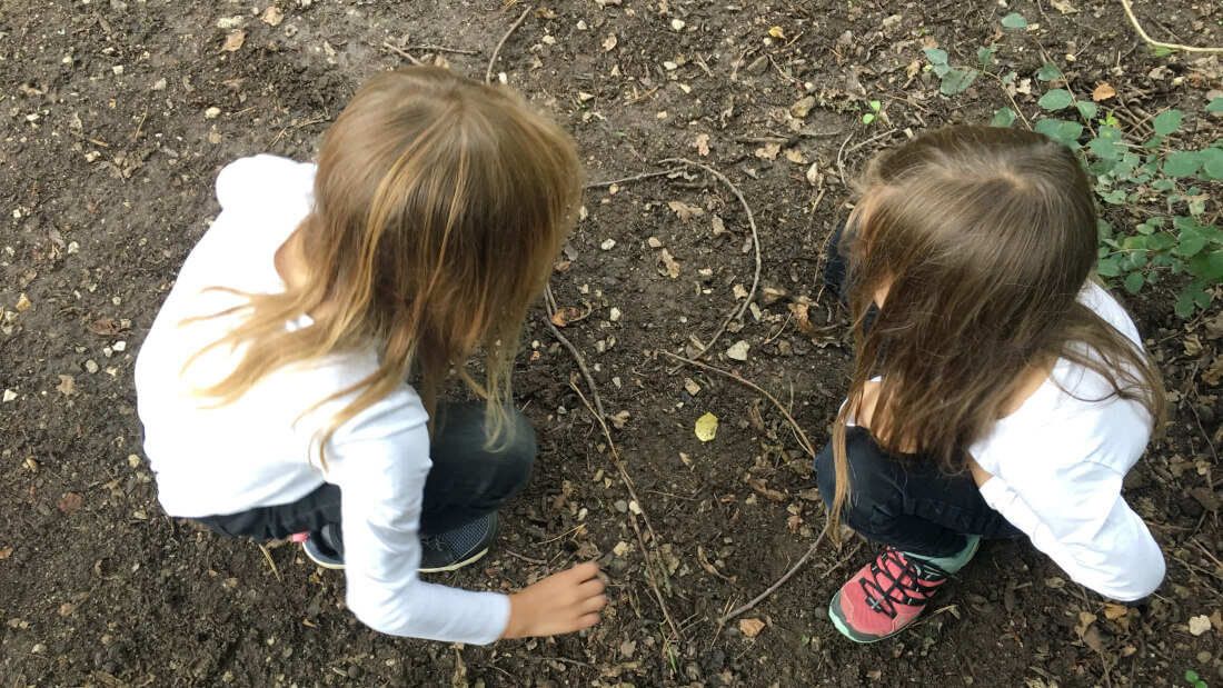 Die Kinder legen bei einer Aufgabe der Wald-Schatzsuche Schmetterlinge aus Zweigen